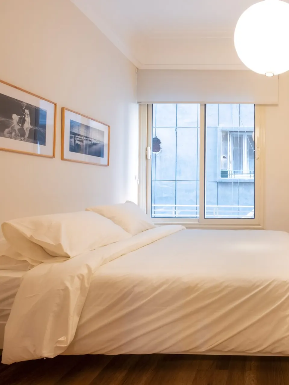 Bright bedroom with crisp white linens, framed art and a sunlit window